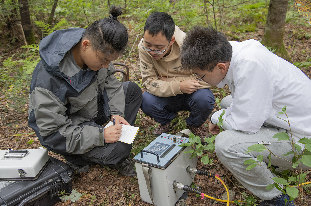 three people crouching around a geophysics instrument 