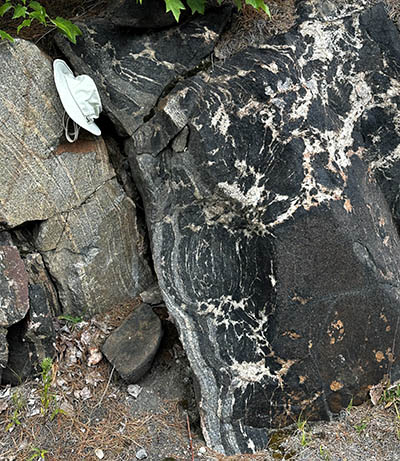 a rock outcrop with a white hat used for scale