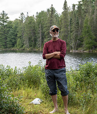 A smiling Grant Ferris in bare feet standing in front of a pond 