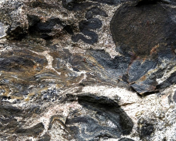 rocks with swirling shaped patterns and light and dark colours showing different rock types and shapes