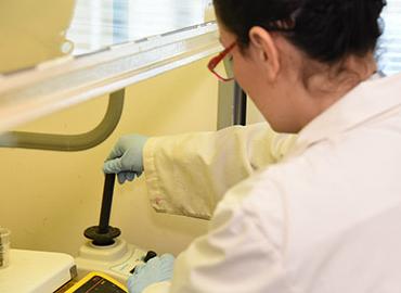 a scientist reaching into a fume hood