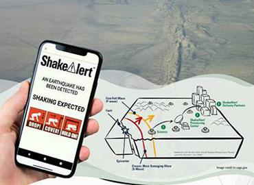 a cell phone showing a shake alert app with a earthquake schematic diagram and photo of a fault line in the backgorund