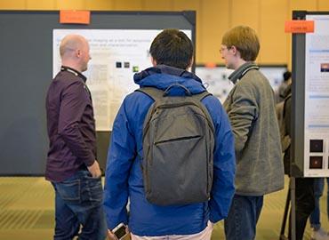 three people looking at posters