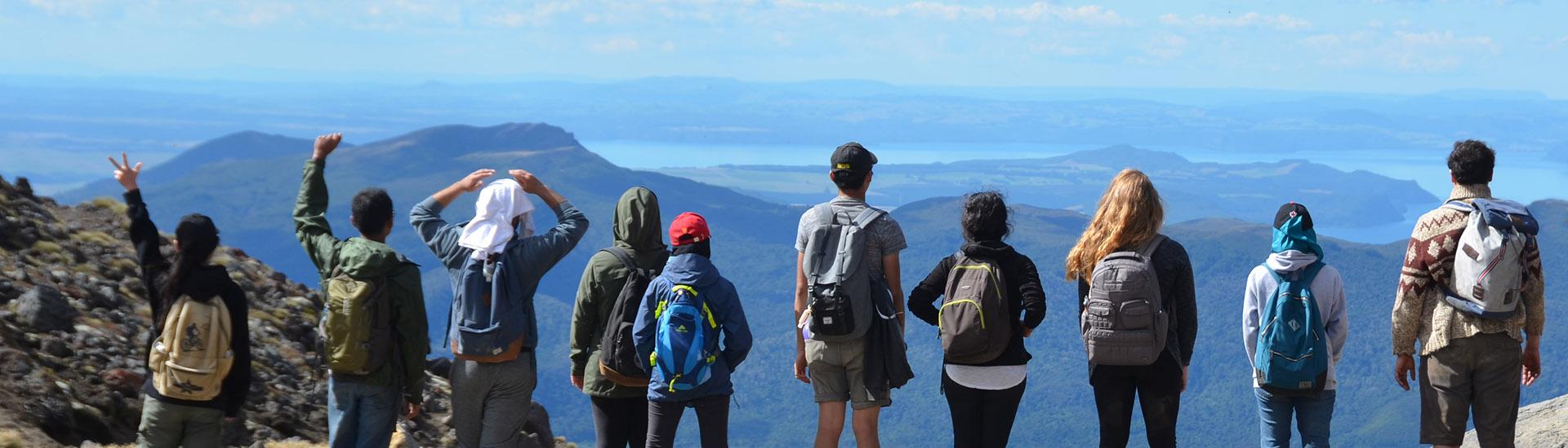 Students standing in a line with looking out over the vista from a volcano top