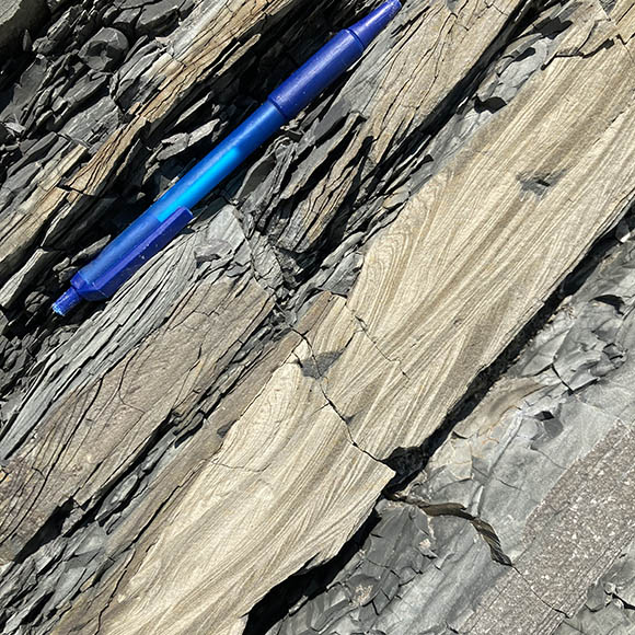 diagonal layers of brown and grey with a blue pen on the top left for scale